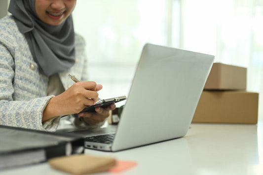 Asian Muslim woman small business owner using laptop to explore business opportunities online.