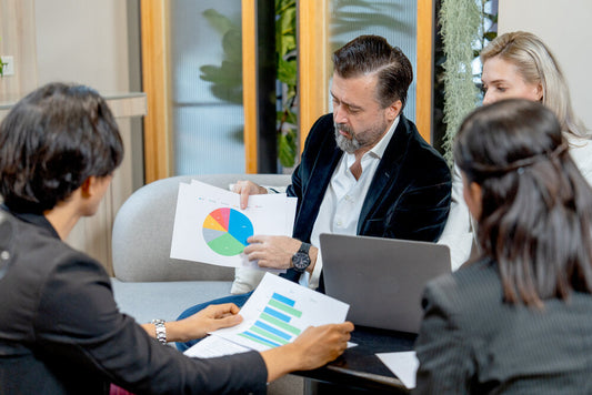 Group of diverse business professionals discussing data and charts, representing a market research business for sale.