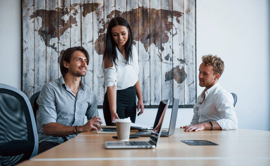 Young business professionals in formal attire collaborating in a modern office in 2025, representing the global marketplace to buy or sell a business.
