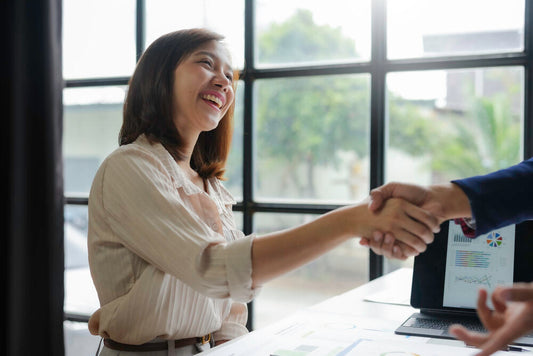 Asian business owner shaking hands after successful business sale in the UK