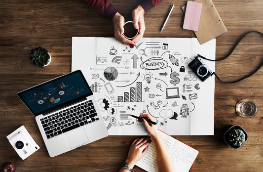 Image showing a business consultant explaining key factors of business valuation to a client, with charts and financial documents on the table, symbolizing the process of determining a business's value and selling a business.