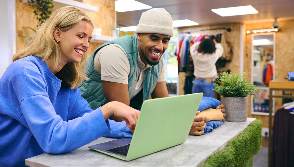 Couple smiling together inside a retail store, representing happy business owners.
