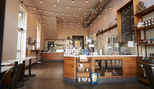 Interior of a coffee shop for sale in Austin, Texas featuring modern espresso machines, wooden tables, and cozy seating